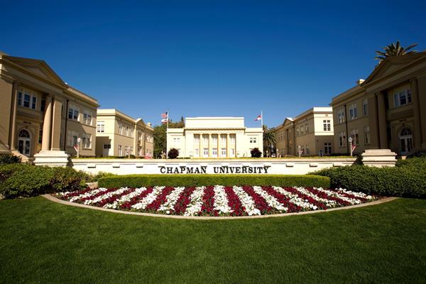 green campus with white and red flowers with Chapman University sign